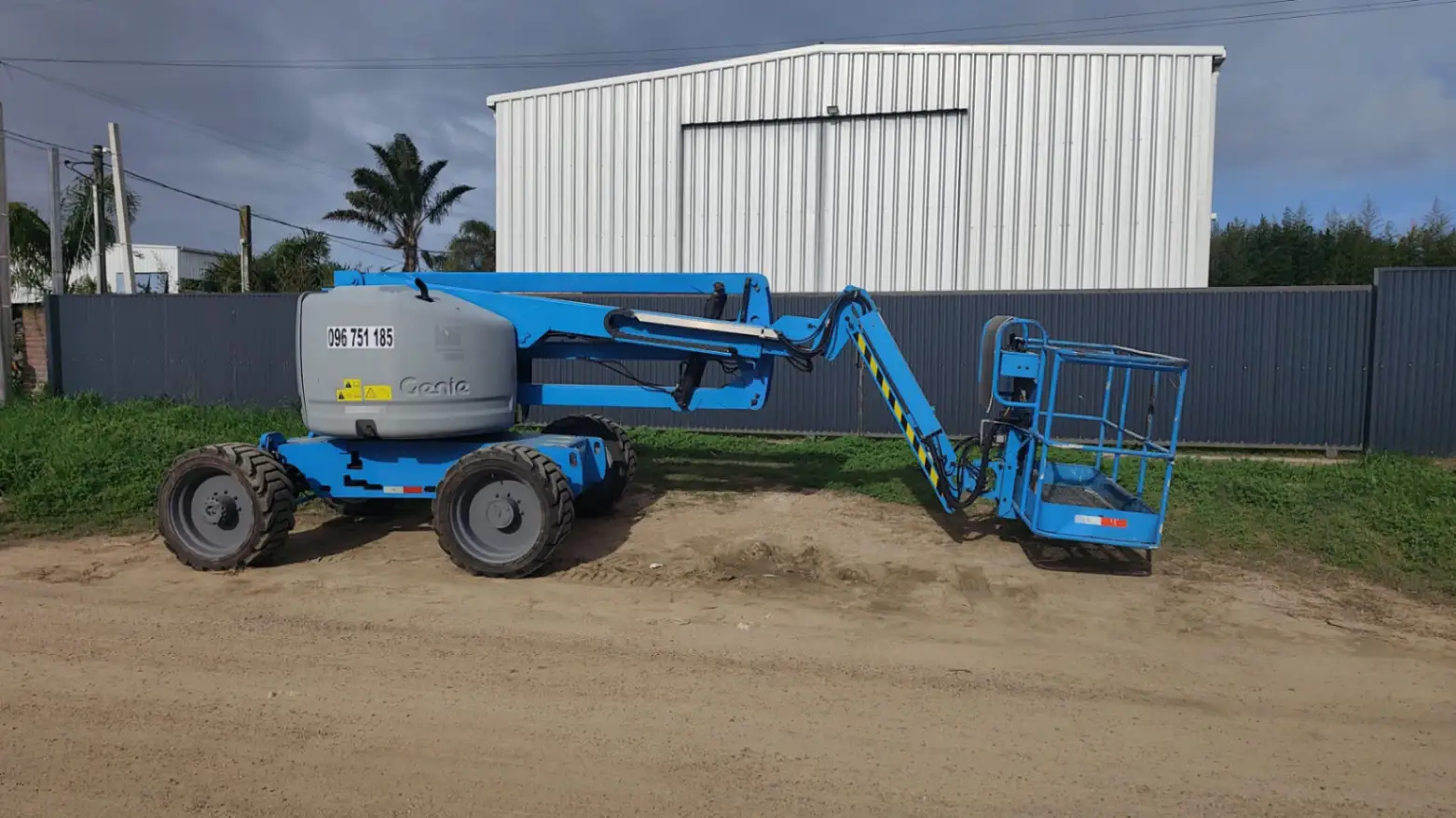 Plataforma elevadora Genie estacionada junto a galpón industrial al atardecer en Uruguay