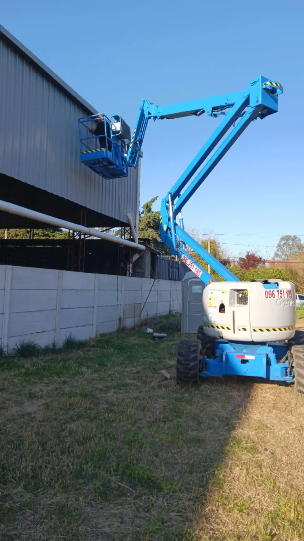 Plataforma elevadora Genie trabajando en fachada de galpón industrial en Uruguay