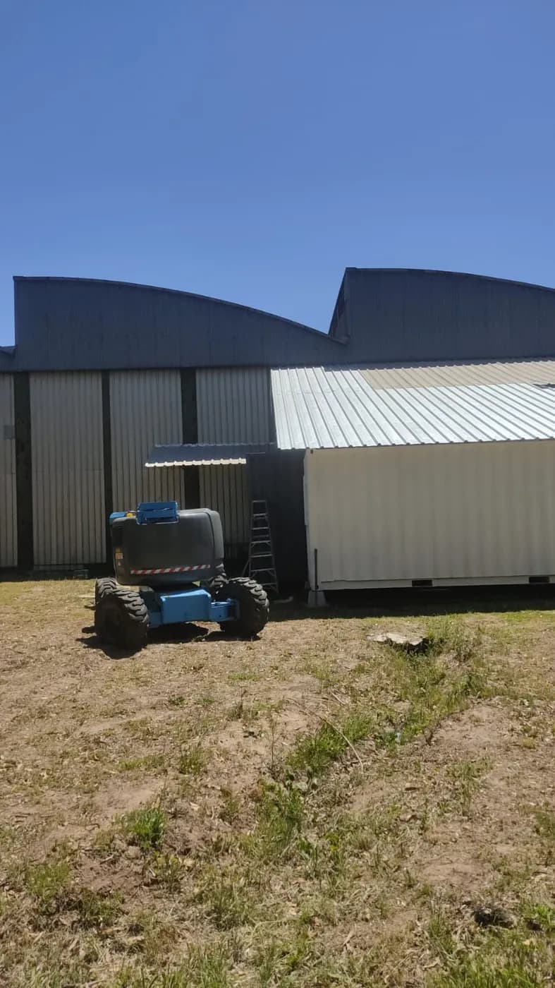 Plataforma elevadora Genie junto a galpones industriales en Uruguay