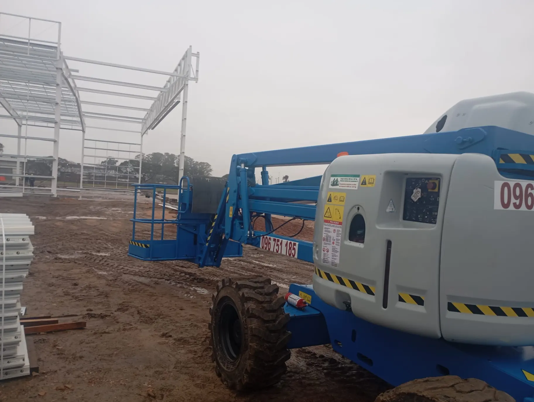 Plataforma elevadora Genie junto a estructura metálica y paneles de obra en Uruguay